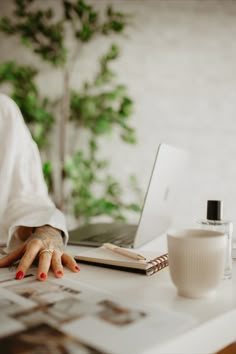 a woman sitting at a desk with her hands on the keyboard and laptop computer in front of her