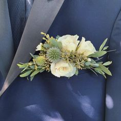 a boutonniere with white flowers and greenery on the lapel of a blue suit