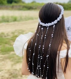 the back of a woman's head with beads and pearls on it, wearing a white dress