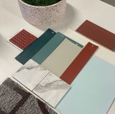 several different colors of tile on a table next to a potted plant and rug