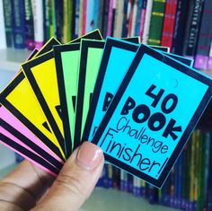 a hand holding four stickers that say 40 book challenge finisher