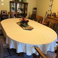 a white table cloth with flowers on it in front of a china cabinet and clock