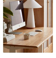 a wooden desk with a computer on it and a lamp in the corner next to it