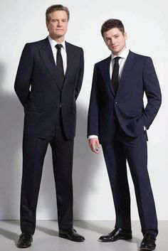 two men in suits standing next to each other with their hands on their hipss