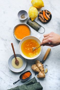 the ingredients to make this soup are laid out on a marble counter top, including carrots and ginger