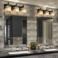 a bathroom with two sinks and three mirrors on the wall above them is lit by lights