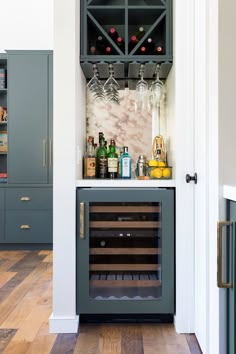 an open wine cabinet with bottles and glasses on the top, in front of a wooden floor