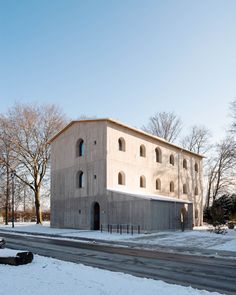 the building is made out of concrete and has arched windows on each side, along with a parking lot in front of it