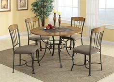 a dining table with four chairs and a bowl of fruit