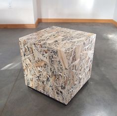 a large wooden cube sitting on top of a floor in an empty room next to a wall