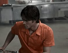 a man in an orange shirt sitting at a table