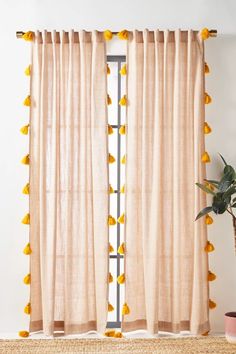 a window with yellow pom - poms hanging from it's curtain rod