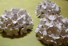 three white flowers sitting on top of a green cloth covered table next to each other