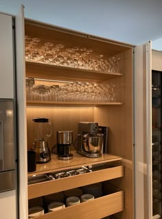 an open cabinet with many glasses and coffee maker