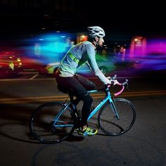 a person riding a bike in the street at night with blurry lights behind them