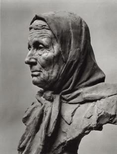 a black and white photo of an old woman's head with a hood on