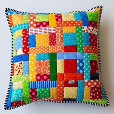 a colorful patchwork pillow on a white wall