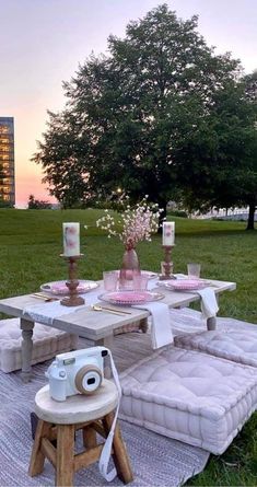 a picnic table set up in the middle of a field with flowers and candles on it