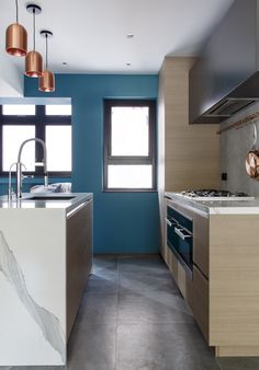 a kitchen with blue walls and marble counter tops, an oven and sink are in the foreground