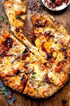 two slices of pizza sitting on top of a wooden cutting board next to a bowl of sauce