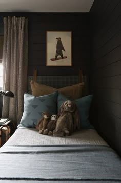 two stuffed animals sitting on top of a bed in a room with wood paneling