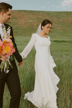 a bride and groom holding hands while walking through tall grass on their wedding day in an open field