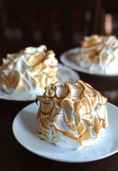 two white plates topped with desserts on top of a wooden table