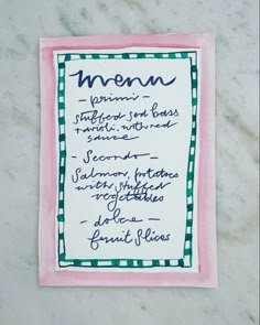 a menu with writing on it sitting on top of a marble countertop next to a knife