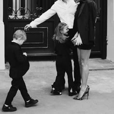 a woman and two children standing in front of a door