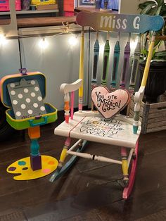 a child's rocking chair with a heart shaped sign on it and other toys in the background