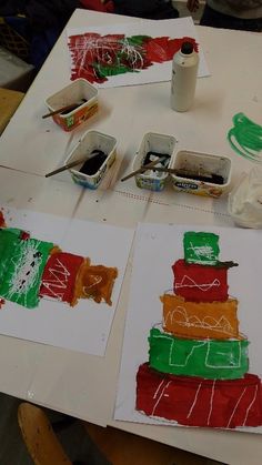 two children's art projects are being displayed on a table with paint and crayons