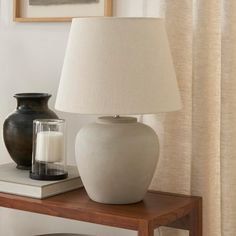 a white vase sitting on top of a table next to a lamp