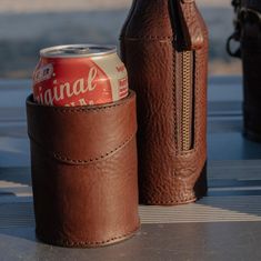 two brown leather can coolers sitting on top of a metal table next to each other