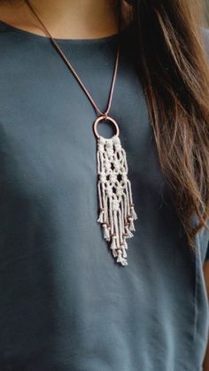 a woman wearing a necklace with beads and chains hanging from it's back end