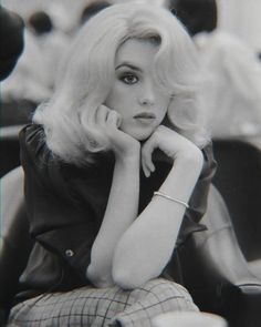 a black and white photo of a woman sitting at a table with her hand on her chin