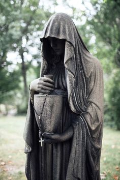 a statue of a woman holding a bucket in her hands and wearing a hooded cloak