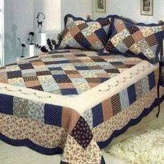 a bed with a blue and brown quilt on top of it next to a window