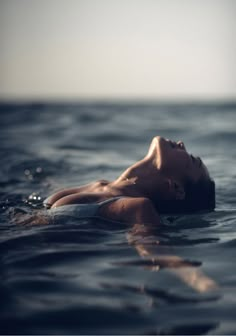 a woman floating on top of a body of water in the middle of the ocean