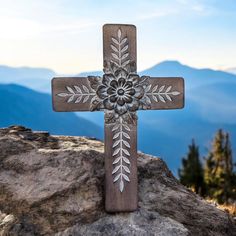 a wooden cross sitting on top of a rock