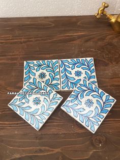 four blue and white tiles sitting on top of a wooden table