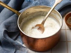 a pot filled with white liquid next to a wooden spoon on top of a blue towel