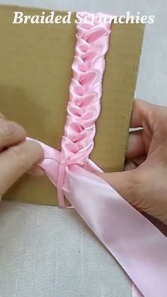 someone is tying a pink ribbon around a box