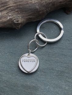 a silver keychain with the word forever on it and a heart shaped tag