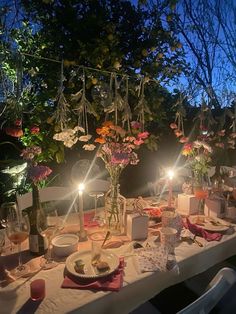 a dinner table set up with candles and flowers in vases, plates and napkins