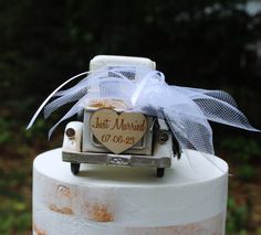 a wedding cake with an old fashioned car on top and a bow tied to it