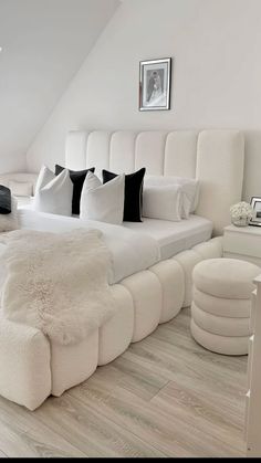 a large white bed sitting in the middle of a bedroom