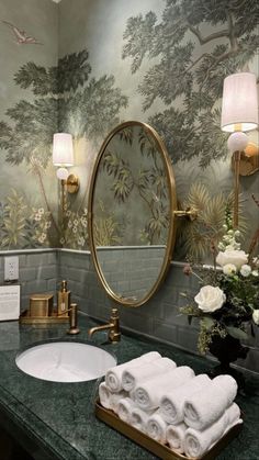 a bathroom with green marble counter top and wallpapered mural behind the sink area