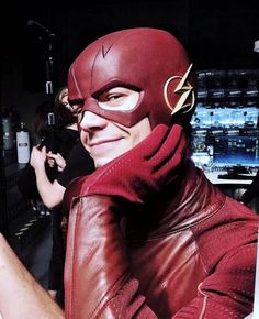 a man in a red leather jacket taking a selfie with his cell phone while wearing a flash costume