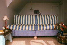 a blue and white striped couch sitting in a living room next to a wooden table