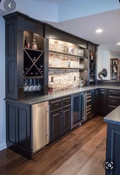 a large kitchen with black cabinets and stainless steel appliances in the center, along with wooden flooring